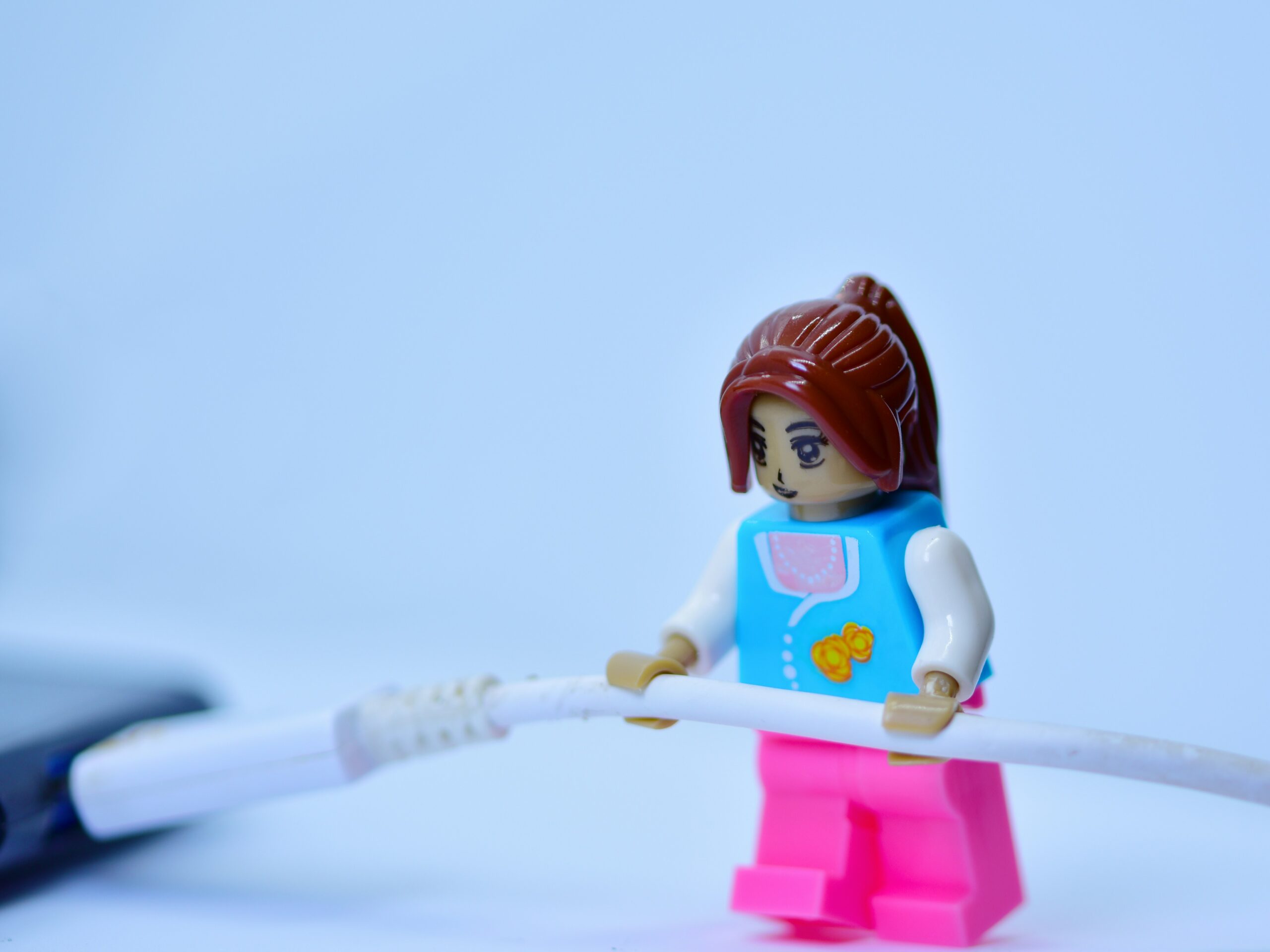 LEGO minifigure holding a white cable against a light blue background